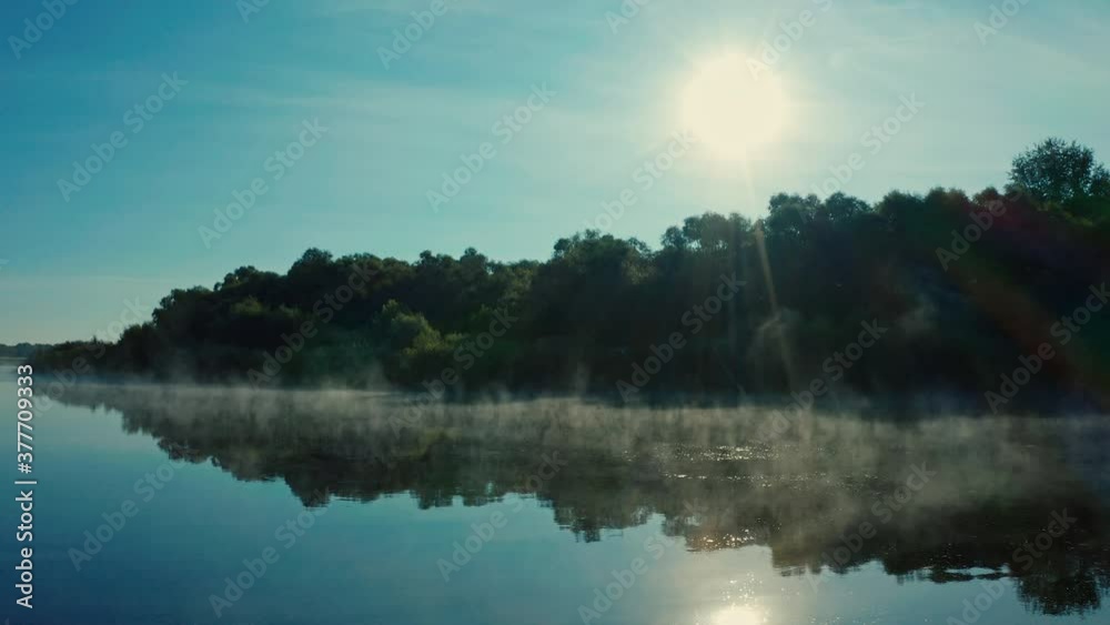Drone flies close to water surface while morning evaporation. Beautiful morning landscape with a fog while sunrise. Aerial view of sunrise above river Desna, Ukraine. Water evaporation over the lake Drone flies close to water surface while morning evaporation. Beautiful morning landscape with a fog while sunrise. Aerial view of sunrise above river Desna, Ukraine. Water evaporation over the lake