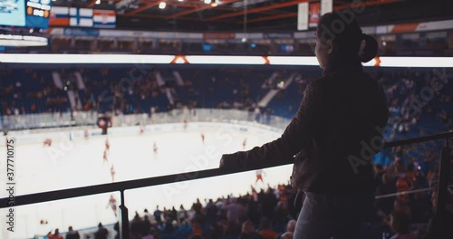 Girl watching sports on hockey arena. Slow motion. Female hockey fan. photo