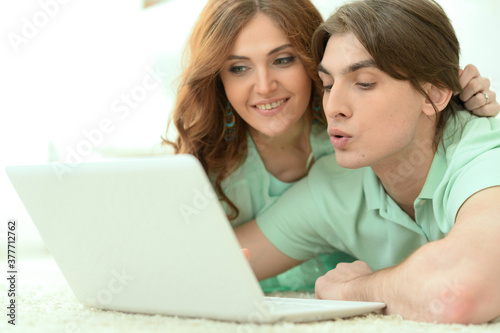 Happy young couple looking at laptop while lying on floor © aletia2011