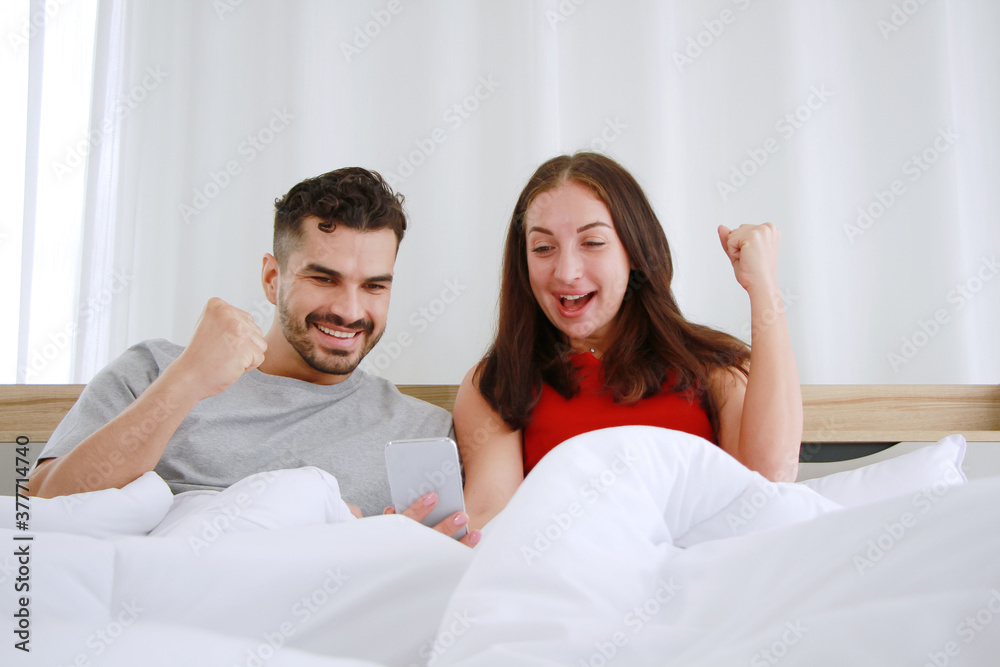 Smiling Caucasian Couple love relaxing and funny for shopping online in social media with smartphone in bedroom. Technology and lifestyle on holiday of family Concept. Smiling Caucasian Couple love relaxing and funny for shopping online in social media with smartphone in bedroom. Technology and lifestyle on holiday of family Concept.