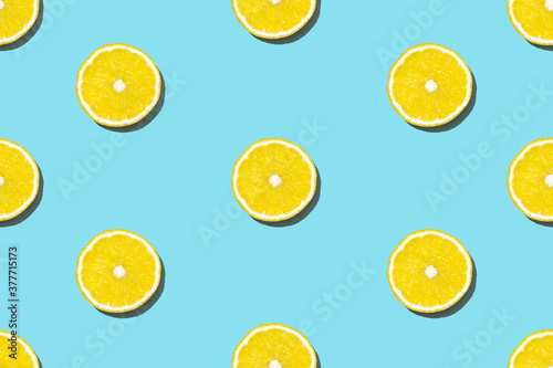 Top view of fresh lemon pattern on blue background. Many sliced yellow lemon texture background. Seamless fruit minimal concept. © Papin_Lab