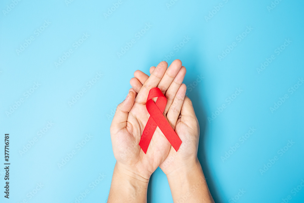 Man holding Red Ribbon for supporting people living and illness. Healthcare and safe sex concept. December World Aids Day Awareness month Man holding Red Ribbon for supporting people living and illness. Healthcare and safe sex concept. December World Aids Day Awareness month
