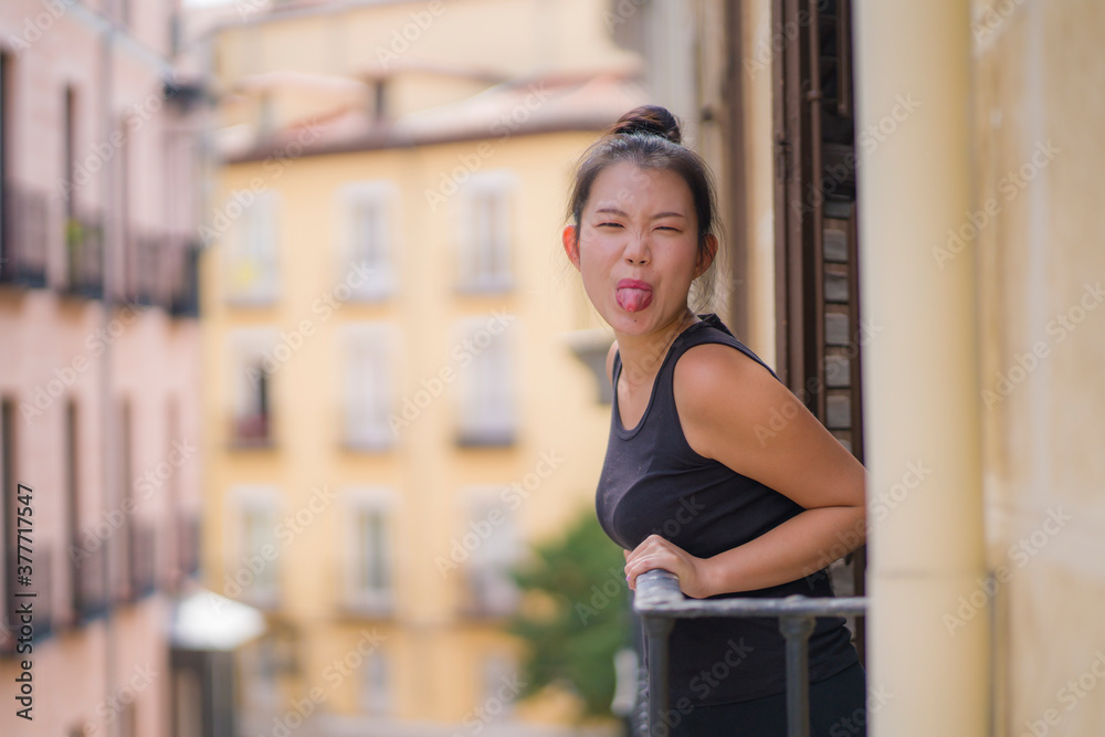 young happy and beautiful Asian Japanese woman in hair bun enjoying city view from hotel room balcony in Spain during holidays trip in Europe smiling cheerful