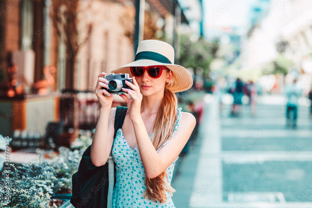 Young woman using her vintage camera while traveling alone