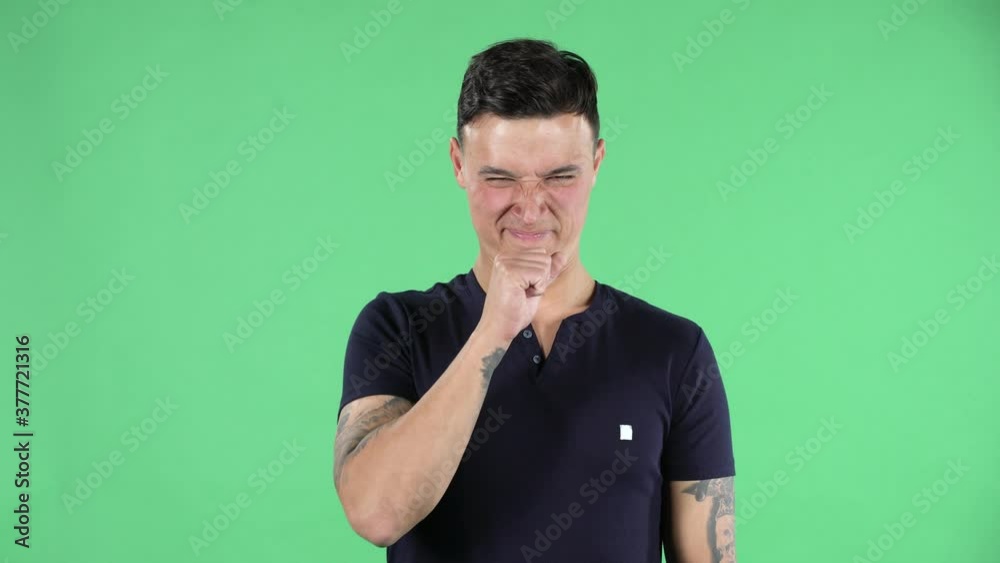 Portrait of a handsome young guy is looking at camera and showing disgust for bad smell or taste. Green screen. Portrait of a handsome young guy is looking at camera and showing disgust for bad smell or taste. Green screen.