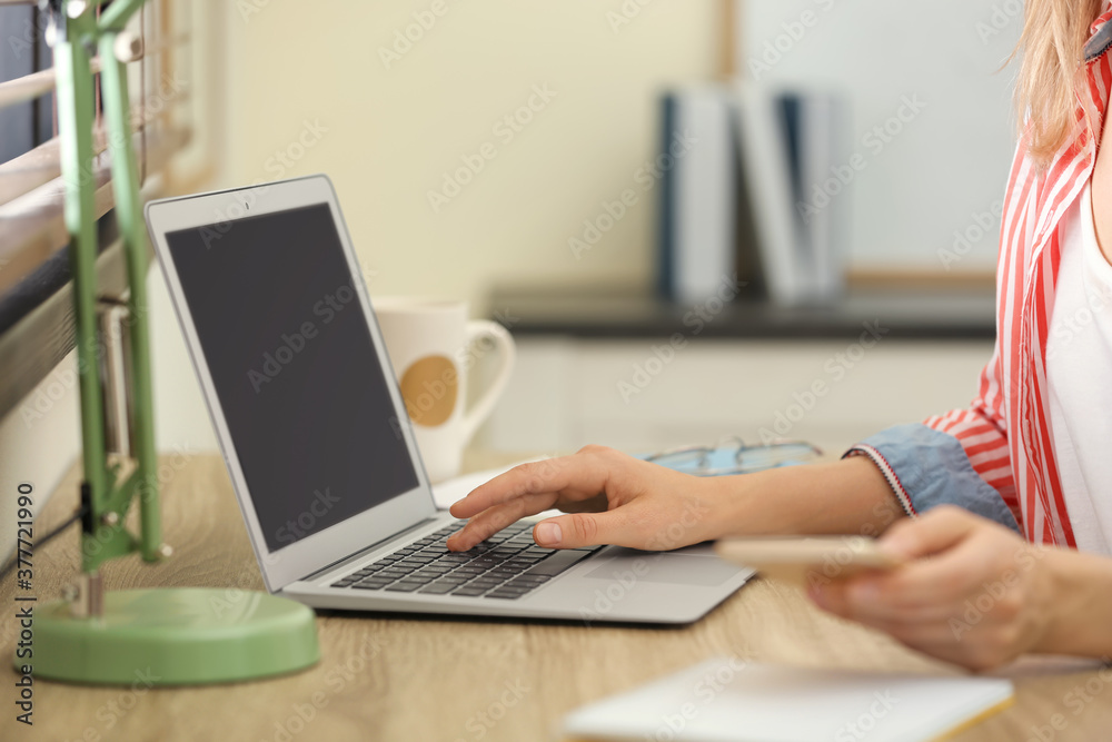 Young woman working on laptop at table, closeup Young woman working on laptop at table, closeup