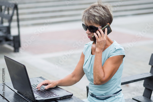 Fashion business senior woman with phone and notebook in blue dress  photo