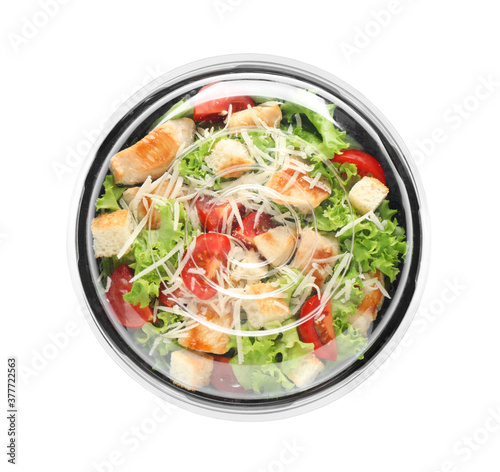 Delicious fresh salad in plastic container with lid on white background, top view