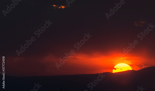 Fototapeta Naklejka Na Ścianę i Meble -  Sunset sky, big sun set over the mountains. 