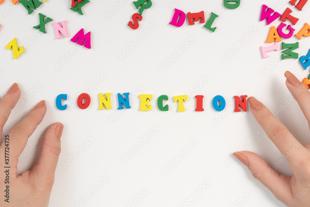 Female hands lay out the word connection from colored letters Female hands lay out the word connection from colored letters