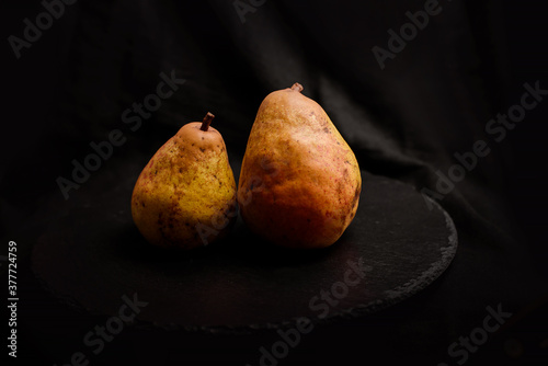 Two yellow pears over a black background.