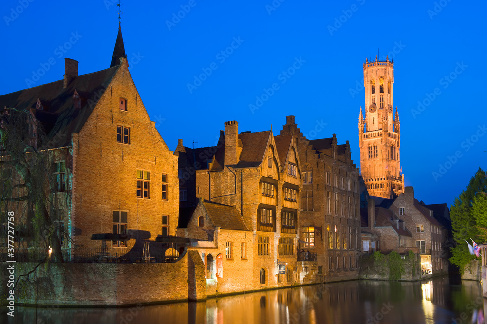 Illuminated Belfry and buildings along Rozenhoedkaai at dusk, Historic centre of Bruges, Belgium, Unesco World Heritage Site.