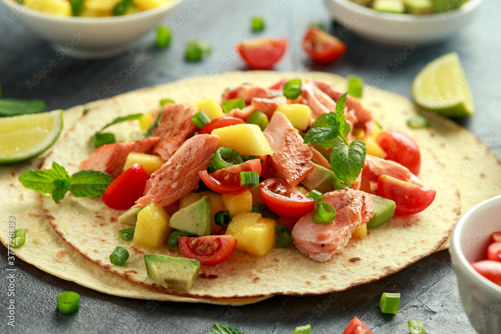 Salmon fish tacos with mango, avocado, tomato, spring onion and lime. Mexican food Salmon fish tacos with mango, avocado, tomato, spring onion and lime. Mexican food