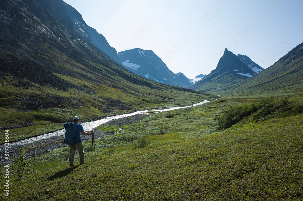 Hiking in Swedish Lapland. Man trekking alone next to Nallo mountain in northern Sweden. Arctic nature of Scandinavia in summer day