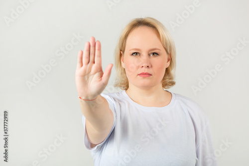 beautiful young plump woman in white t-shirt on white background with hand gesture