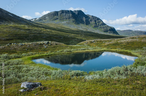 Picturesque Swedish Lapland landscape. Mountain reflecting in small lake along King's trail in northern Sweden. Arctic environment of Scandinavia in summer sunny day