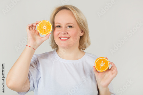 beautiful young plump woman in a white t-shirt on a white background with an orange