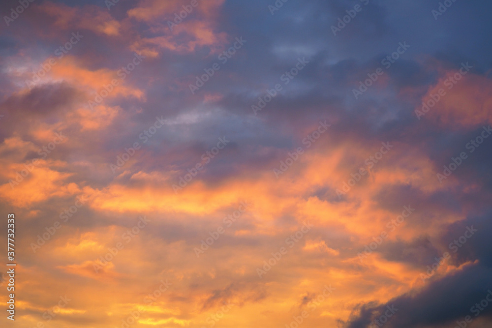 Cloudy sky at sunset. Dark purple and yellow natural background or wallpaper. The rays of the setting sun effectively illuminate the clouds. Beautiful and spectacular evening skies