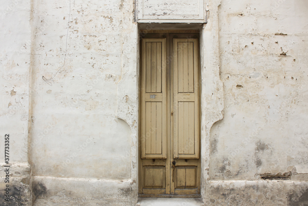 Typical Maltese yellow wooden old door on the limestone wall. Malta. Concept of traditional Maltese street view, vintage architecture.
