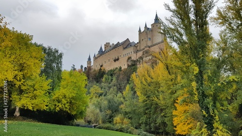 Alcazar de Segovia Spain in fall autumn landscape with tourist monument and yellow colorful nature ochre
