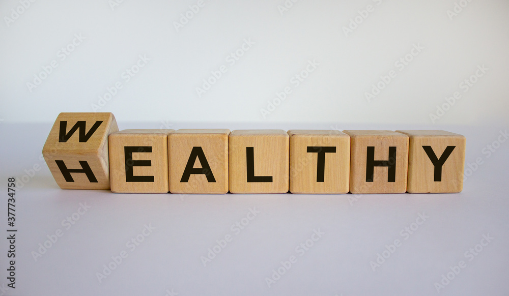 Tturned a cube and changed the word 'Healthy' to 'Wealthy'. Beautiful white background. Business concept. Copy space. Tturned a cube and changed the word 'Healthy' to 'Wealthy'. Beautiful white background. Business concept. Copy space.