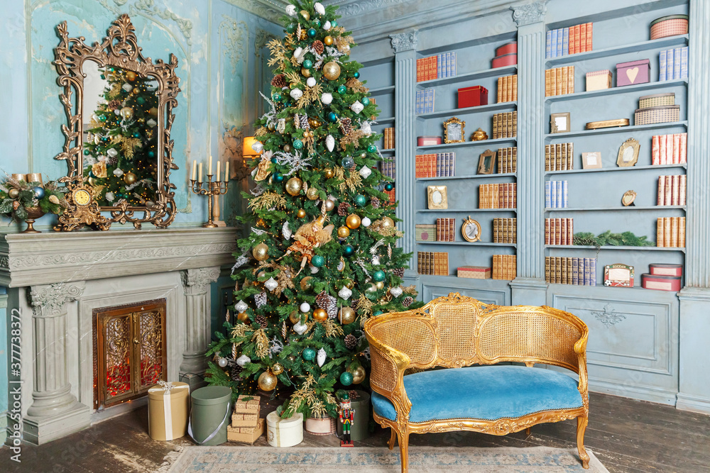 Classic Christmas New Year decorated interior room home library with fireplace. Christmas tree with gold ornament decorations. Modern classical style interior design apartment. Christmas eve at home.
