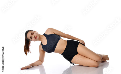 Young brunette woman in sportswear trains on a white background.