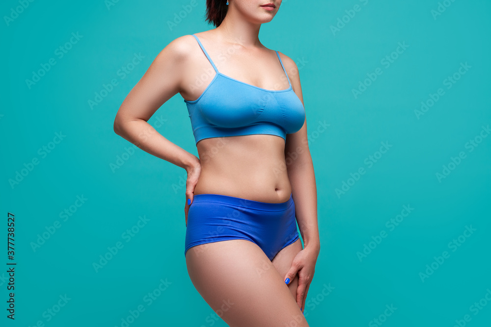 Fototapeta premium Beautiful sexy woman in blue underwear on turquoise background, perfect female body