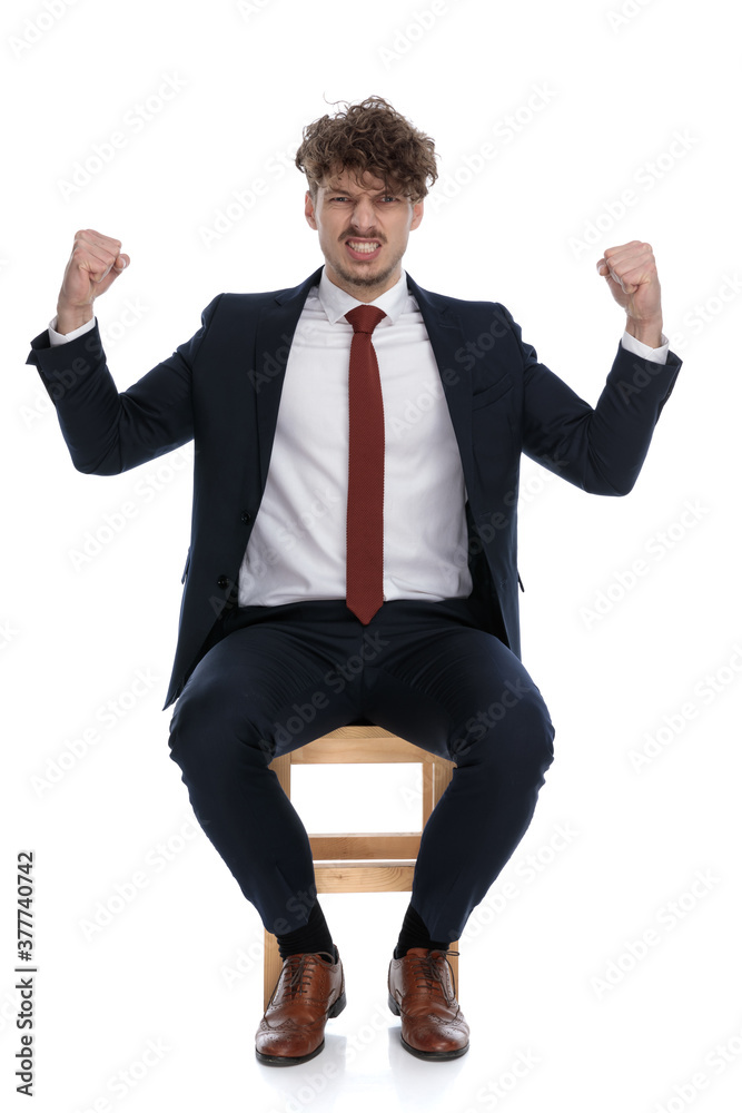 handsome businessman celebrating succes with both his fists up