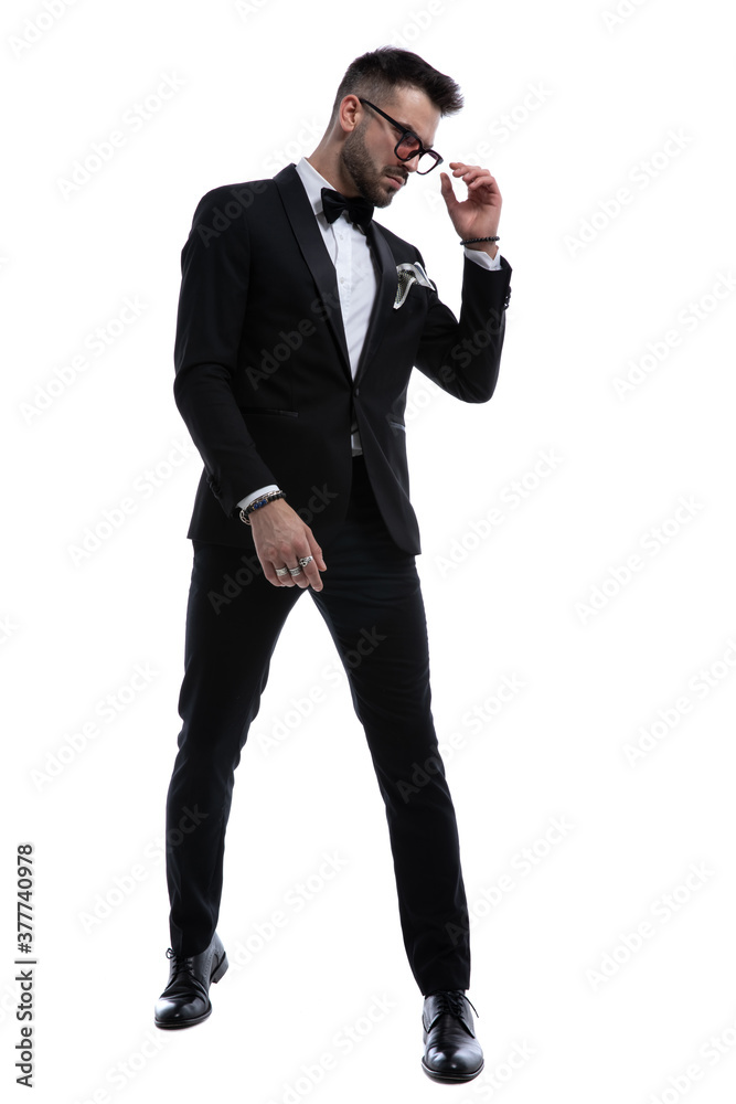 Fototapeta premium cool young businessman in tuxedo fixing sunglasses