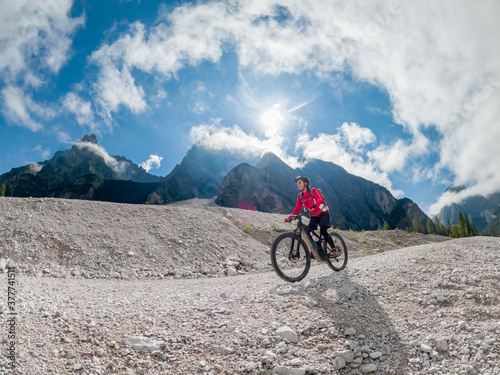 pretty senior woman riding her electric mountainbike in the Innerfeld Valley in the Sexten Dolomites near village of Innichen , Tre cime National park, South Tirol, Italy 