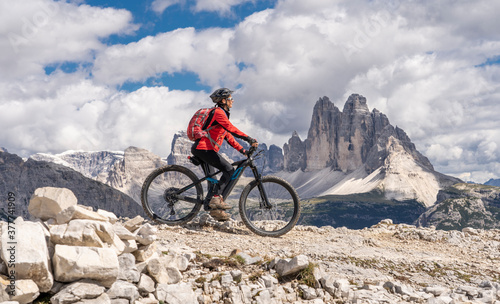 nice senior woman, riding her electric mountain bike below the famous Three peak of Lavaredo in the Sexten Dolomites in South tyrol, Italy