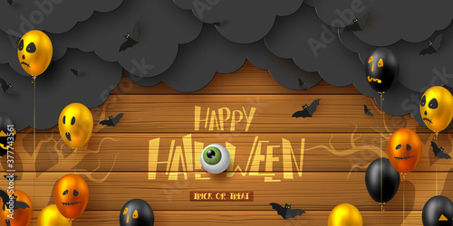 Happy Halloween horizontal banner. Glossy balloons with monster faces, flying bats and paper dark clouds. Handwritten lettering with eye on wooden background. Vector illustration.