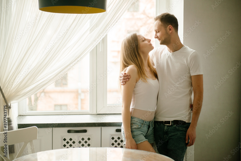 Enjoying nice morning together. Beautiful young couple bonding to each other and smiling while sitting in the kitchen together and having breakfast Enjoying nice morning together. Beautiful young couple bonding to each other and smiling while sitting in the kitchen together and having breakfast