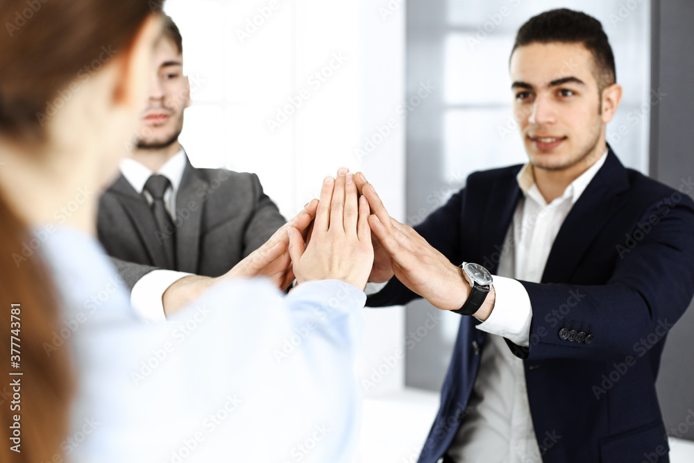 Business people group showing teamwork, joining hands and giving five to each other in modern office. Success concept Business people group showing teamwork, joining hands and giving five to each other in modern office. Success concept