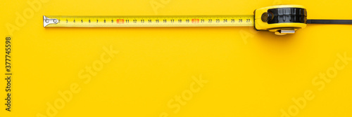 Tape measure on the yellow background with copy space. Panoramic photo of yellow tape measure. photo