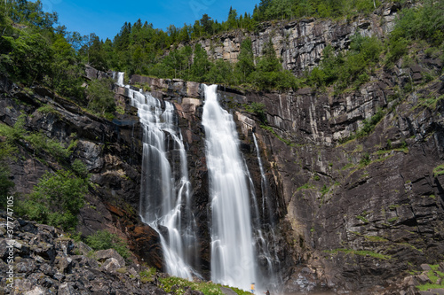 Skjervsfossen waterfall, on the road between Granvin and Voss, Hordaland, Norway. Impressive beautiful win falls plunging 150 metres in a narrow canyon