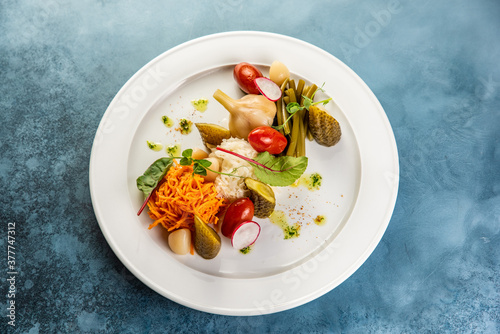 Slices various pickled vegetables on white plate in restaurant