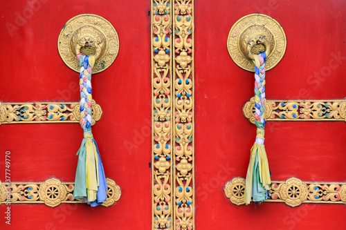 Ornate door handles and prayer scarves on ancient Buddha park monastery at Ravangla in South Sikkim, India. Red color door at Buddha Park of Ravangla. Door handles at Buddha Park Monastery in Sikkim. photo