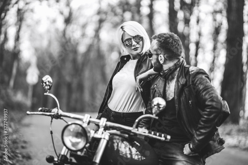 Pretty couple near motorcycle on the road in the forest with blured background