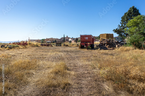 Agricultural machines used to harvest wheat. Dry field at the Spanish countryside. Traditional village at the background. Straw bales used as livestock forage. Sebúlcor, Soria, near Madrid, Spain