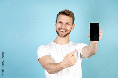 Adult guy pointing on modern smartphone with blank screen