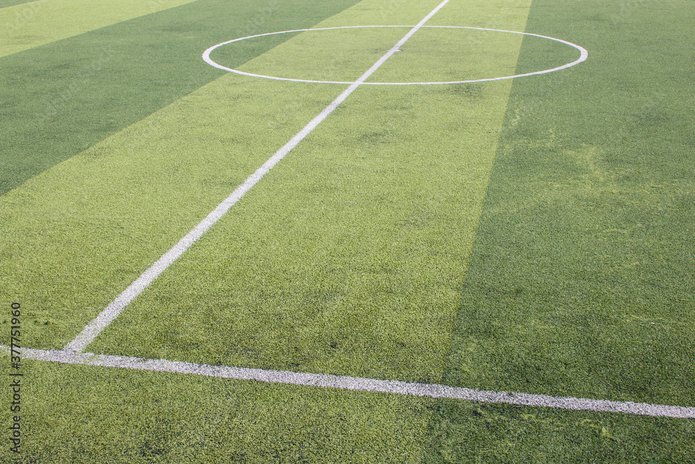 Photo of a green synthetic grass sports field with white line shot from above.