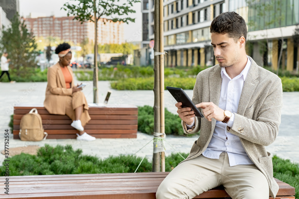 Young serious businessman in formalwear pointing at screen of digital tablet Young serious businessman in formalwear pointing at screen of digital tablet