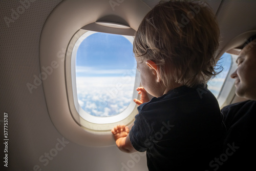 cute toddler points his finger at the sky through the window. first flight concept, traveling with children.
