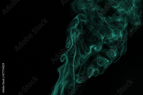 green smoke from incense on a black background