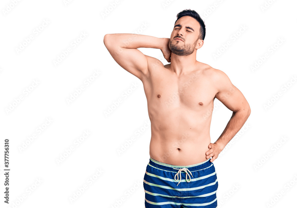 Young handsome man wearing swimwear suffering of neck ache injury, touching neck with hand, muscular pain
