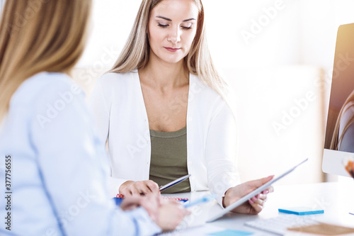 Business woman toned portrait in sunny office. Businesspeople or colleagues at meeting while sitting at the desk. Casual clothes style. Audit, tax or lawyer concept