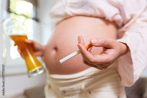 a pregnant woman with a beer and a cigarette in her hand