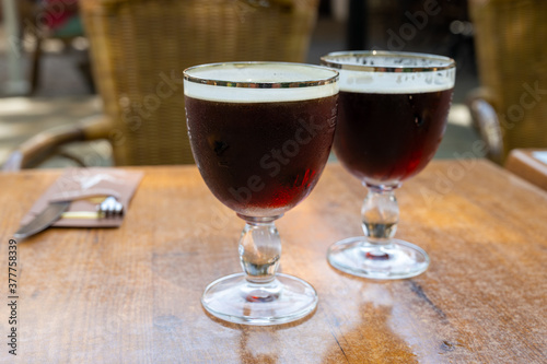 Obraz na plátně Glasses with cold dark strong Belgian beer served outdoor